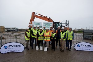 Dignitaries at the building site with a digger behind